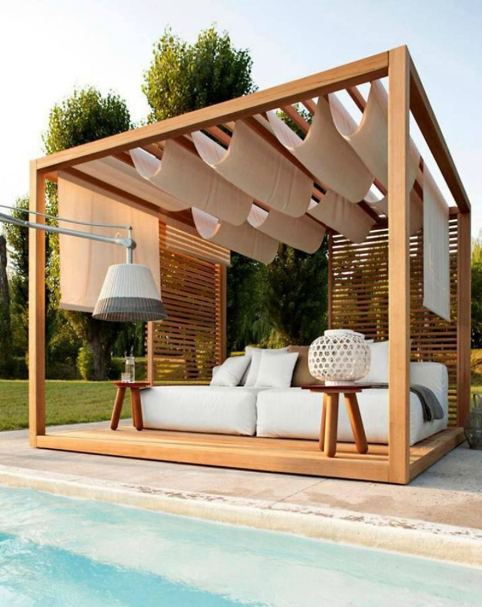 A wooden pergola with a lattice roof and lattice sides, featuring a comfortable seating area in a relaxed garden environment.