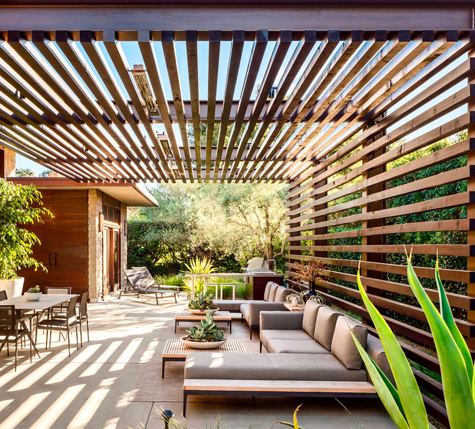 A wooden pergola in a beautiful garden, filled with pretty plants and bright light.